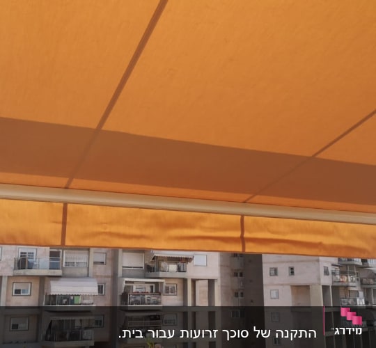 סוכך כתום עם מסגרת לבנה במרפסת